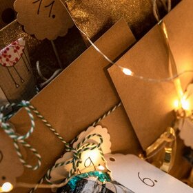 Mit einer Lichterkette warm beleuchtete Geschenke, die mit Nummern zwischen 1 und 24 beschriftet sind.