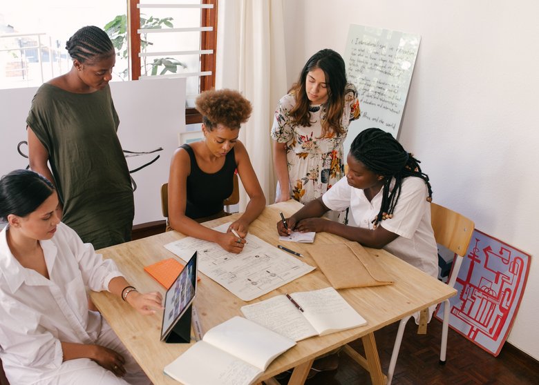 Cours Cinq femmes assises autour d'une table travaillent ensemble
