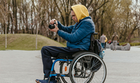 Eine Person im Rollstuhl macht ein Foto mit einer Spiegelreflexkamera