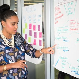 Une femme montrant un tableau où de multiples choses sont écrites