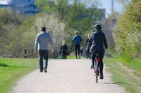 Différentes personnes dans un parc, à droite, l'une fait du vélo, à gauche, une autre personne marche