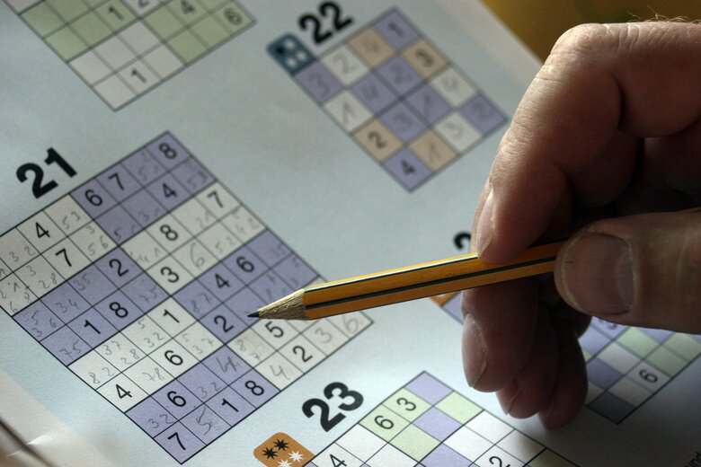 Une personne tenant un crayon complète un sudoku