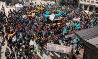 Aufnahme von oben: Viele Menschen stehen versammelt auf einem Platz und halten Schilder und Luftballons in die Höhe