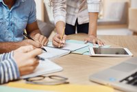 Des personnes autour d'une table regardent des documents