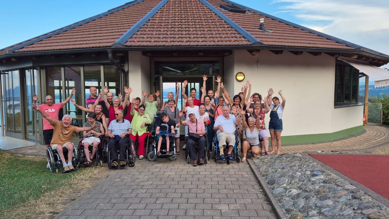 Vacances Des personnes se tiennent debout ou en chaise roulante devant un bâtiment, ils sourient