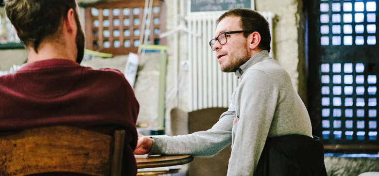 Un homme avec des lunette discute avec un autre homme