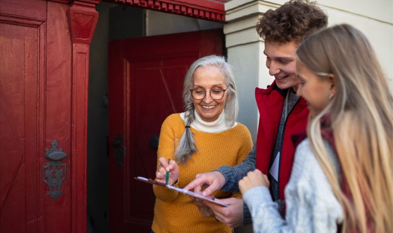 Haustürkampagne Zwei junge Menschen sprechen mit einer älteren Frau an der Haustür und lassen sie ein Formular unterschreiben.
