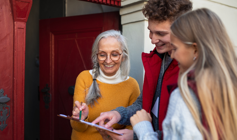 Haustürkampagne mit Solimont Eine ältere Frau an der Haustür im Gespräch mit zwei jungen Menschen. Sie schauen auf ein Klemmbrett.