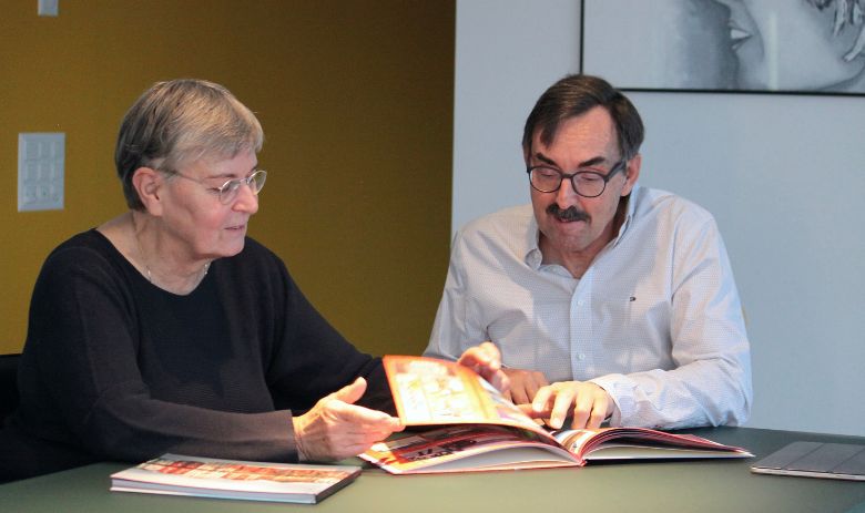 Ein Mann schaut zusammen mit einer Frau ein Fotoalbum an. Sie lächeln beide. 