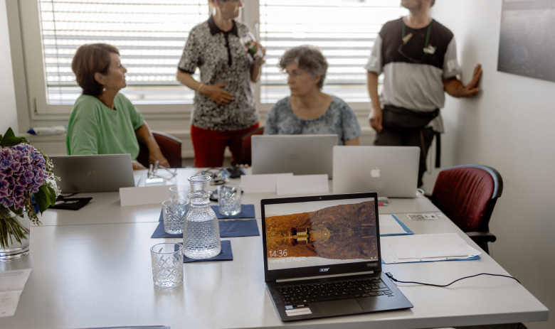 Computerkurs Zürich Eine Kleingruppe an einem Tisch. Darauf sind aufgeklappte Laptops.