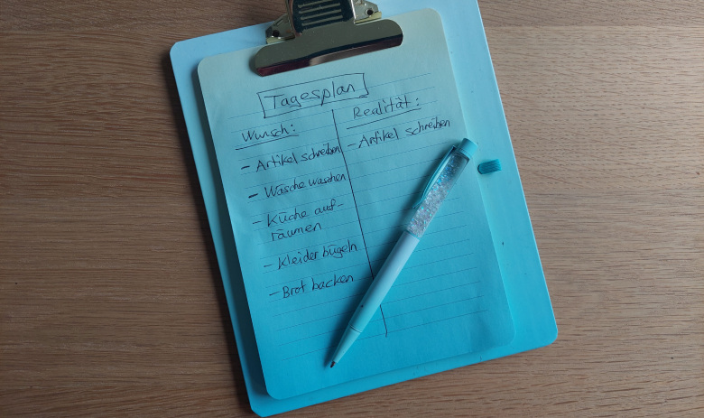 Resilienz und Stärke Kleines Clipboard mit einer Notiz. Als Titel steht "Tagesplan", Wunsch und Realität sind einander gegenübergestellt. Die Wunschliste enthält fünf Aufgaben, auf der Seite "Realität" ist allein der erste Punkt aus den Wünschen übertragen.