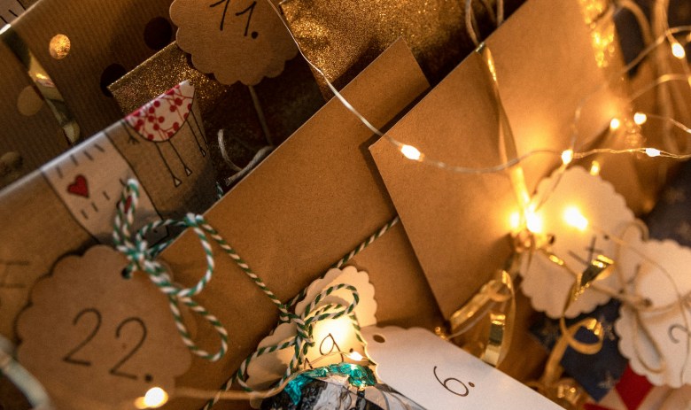 Mit einer Lichterkette warm beleuchtete Geschenke, die mit Nummern zwischen 1 und 24 beschriftet sind.